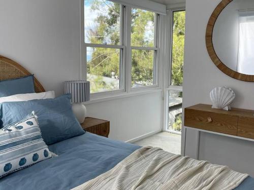 洛恩Seaview Treehouse - three minute walk to the beach的一间卧室配有蓝色的床和镜子