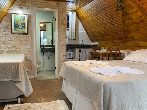 蒙特韦尔迪Chalés Paraíso Monte Verde的一间带两张床的卧室和一间带桌子的厨房