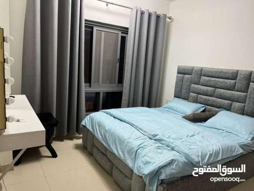 马斯喀特One Bed Room Apartment Muscat Hills的一间卧室配有一张带蓝色床单的床和一扇窗户。