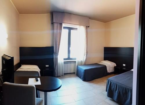拉奎拉Hotel Porta Rivera Plesso Stazione的客房设有两张床、一张桌子和一扇窗户。