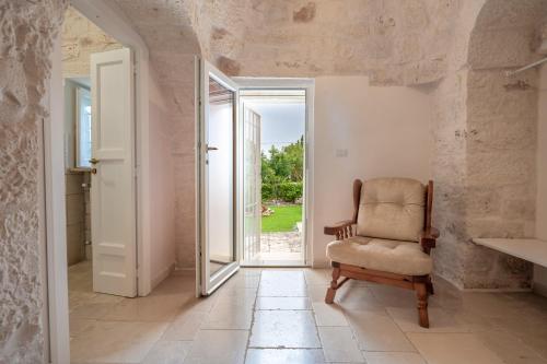 奇斯泰尼诺Trullo Suite in Masseria的一间带椅子和一扇开放式门的房间