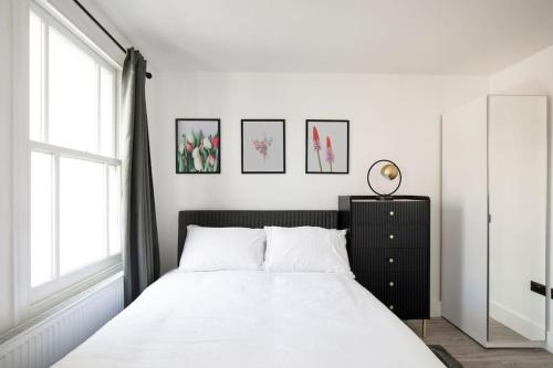 伦敦Spacious Serenity in the Heart of Central London的一间卧室配有一张带白色床单的床和一扇窗户。