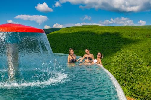 玛特阿哈泽Hotel Ózon & Luxury Villas的三个女人坐在一个带喷泉的游泳池里