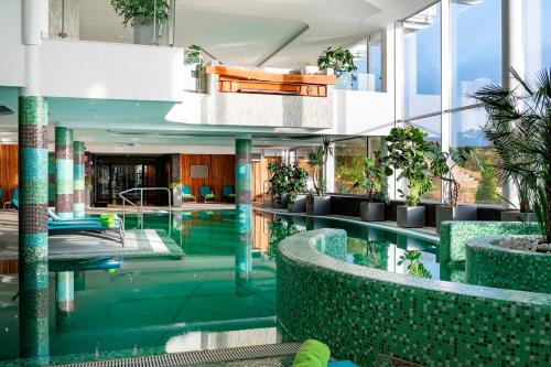 玛特阿哈泽Hotel Ózon & Luxury Villas的植物建筑中的室内游泳池