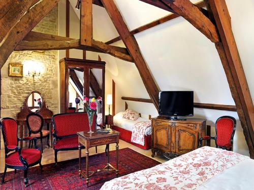 克黑朋Hôtel Le Manoir De Mathan Crépon à la campagne 5 mn d'Arromanches et 10 mn de Bayeux的一间卧室配有一张床和一张桌子及电视