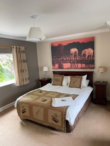 诺里奇Arrandale Lodge的卧室配有一张大床,墙上挂有绘画作品
