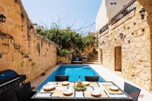 MunxarMatli Farmhouse, your stunning Gozo getaway.的游泳池畔的桌椅