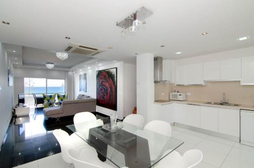 利马索尔海湾宫殿公寓的厨房以及带玻璃桌和白色椅子的客厅。