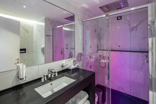 利尼亚诺萨比亚多罗Hotel Monaco的粉红色的浴室设有水槽和淋浴