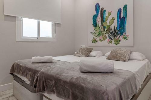 塞维利亚Apartamentos Recaredo 7的卧室内的两张床,墙上有绘画作品