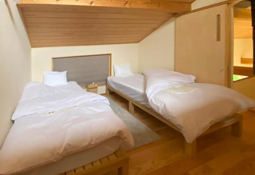 北斗市Garni MonyaMonya/ガルニモニャモニャ的配有白色床单的客房内的两张床
