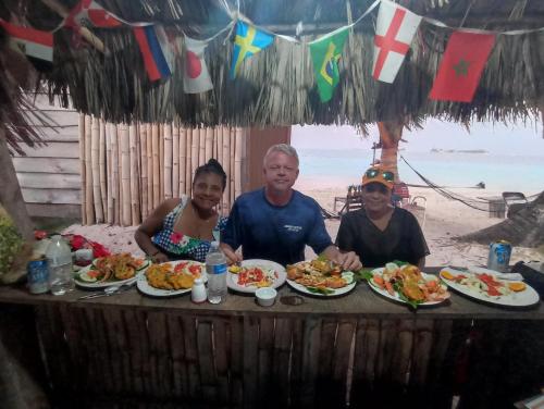 CagantupoIsla diablo cabañas en la orilla del mar baño compartido的一群坐在餐桌上的人,拿着盘子的食物