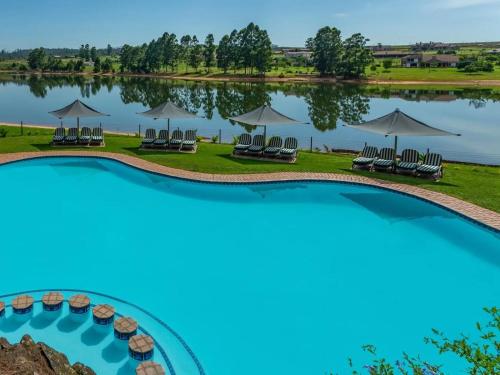 白河Blue Zone Leisure at Pine Lake Inn Resort的享有湖泊的空中景致,配有椅子和遮阳伞