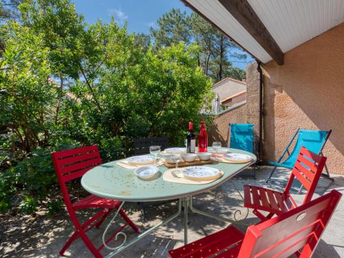 拉卡诺奥肯Holiday Home Les As-9 by Interhome的庭院桌子、红色椅子和瓶装葡萄酒