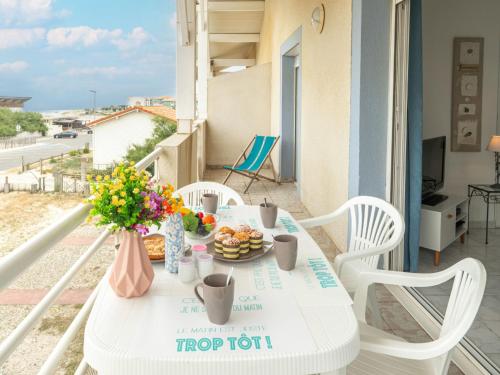 米尼赞海滩Apartment Patguyflor by Interhome的阳台上配有带食物和鲜花的白色桌子