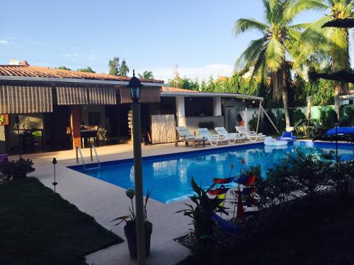 普拉亚科罗纳多B&B EL Litoral的一个带椅子的游泳池和一个棕榈树房子