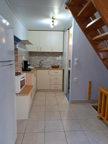 波罗斯Giasemi traditional house的厨房配有白色橱柜和瓷砖地板。