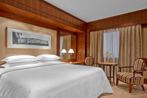 亚松森亚松森喜来登酒店的卧室配有一张白色的大床和一张桌子