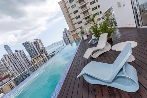 巴拿马城Impressive City View Apartment Marbella - PH Quartier Marbella的一个带椅子的阳台和一个位于大楼内的游泳池
