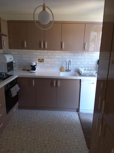 巴恩斯特珀尔Hill's View的厨房配有棕色橱柜和白色用具