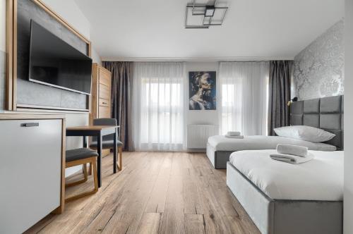 什切青Toress Apartamenty plac Grunwaldzki的酒店客房配有1张床、1张书桌、1张床和1张沙发。