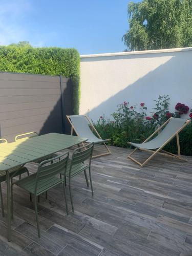 博韦Maison des Larris的庭院配有两把椅子和一张绿色的桌子及椅子