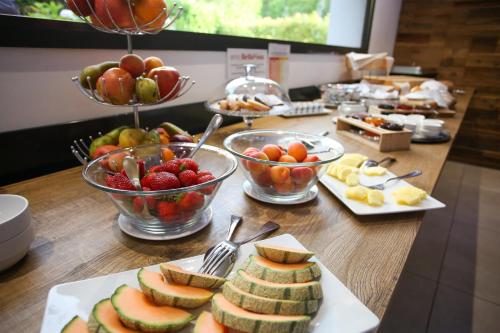 洛迦诺Hotel Bellavista Locarno的桌上放有一碗水果和盘子的食物