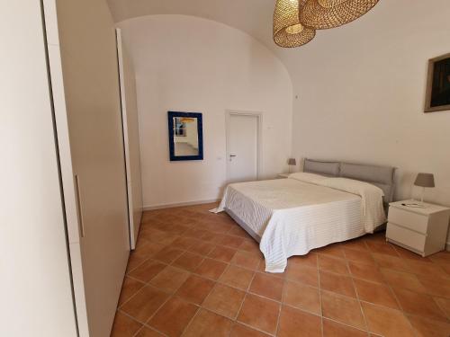 伊斯基亚Casa Dei Nonni的卧室配有白色的床,铺有瓷砖地板。