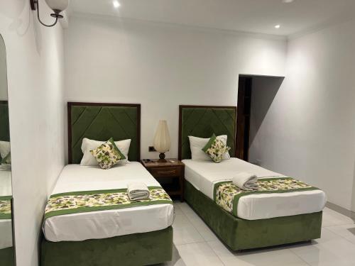 贾夫纳Gatetrees resort的一间卧室配有两张床和一张带台灯的桌子