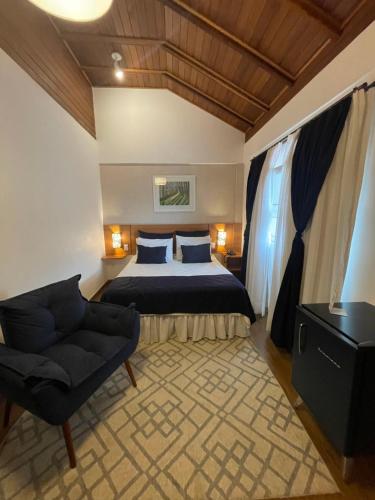 佩尼多Hotel Aromas de Penedo的一间卧室,卧室内配有一张床和一把椅子