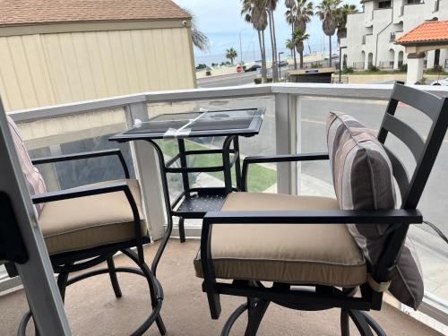 亨廷顿海滩Pacific Breeze Right Next to Huntington Beach Pier! Steps from Beach!!的阳台配有2把椅子和一张桌子,还配有桌子。