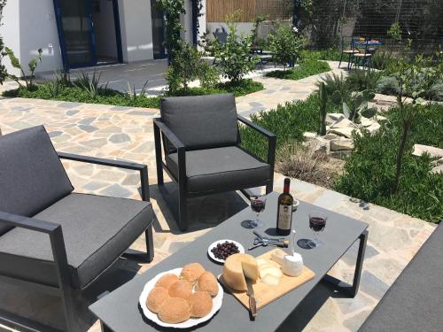 PetrokefálionUTOPIA RESIDENCES Gaia House的庭院配有两把椅子和一张桌子,提供食物和葡萄酒