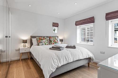 韦尔文Apple Tree Cottage的白色卧室设有一张大床和两个窗户