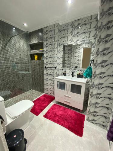 丹吉尔Big appartment near soccer stadium in Tangier的一间带水槽和淋浴的浴室以及红色地毯。