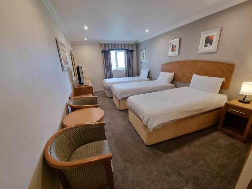 达宁顿堡Kegworth Hotel & Conference Centre的酒店客房,设有两张床和一张沙发