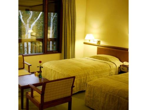 青森Sukayu Onsen Hakkoda Hotel - Vacation STAY 66846v的酒店客房设有两张床、一张桌子和一个窗户。