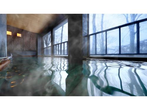 青森Sukayu Onsen Hakkoda Hotel - Vacation STAY 66846v的一间设有窗户的池水客房