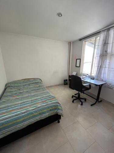 马尼萨莱斯Hermosa y amplia habitación的一间卧室配有一张床、一张桌子和一台电脑