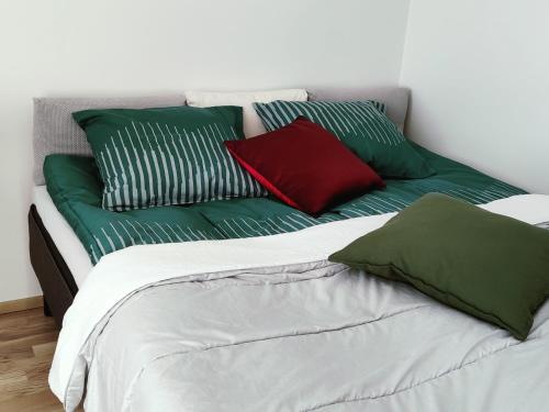 坦佩雷Ydinkeskustassa, uusi yksiö+ autohallipaikka的一张带绿色和红色枕头的床