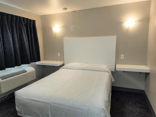 安纳海姆莫拉达宾馆的一间小卧室,配有白色的床和两盏灯