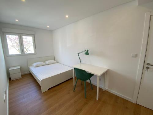 奥埃拉斯Carcavelos Beach Walking distance room的一间卧室配有一张床、一张书桌和一个窗户。