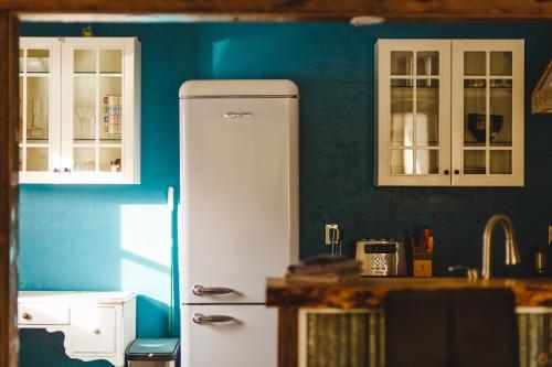 MervilleTiny house & Sauna on Lakefront Farm Oasis的厨房配有白色冰箱和蓝色的墙壁
