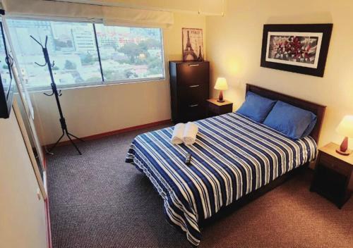 利马Exclusivo Departamento 2BR en San Isidro的一间卧室配有一张带蓝白条纹毯子的床