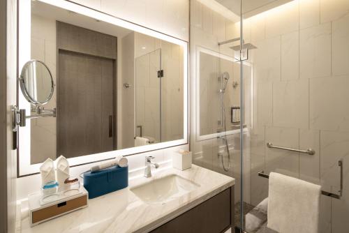 临沂市临沂人民广场凯悦嘉轩酒店的浴室配有盥洗盆和带镜子的淋浴