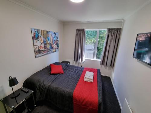 提马鲁Stay Timaru的一间卧室配有一张带红色毯子的床和窗户。