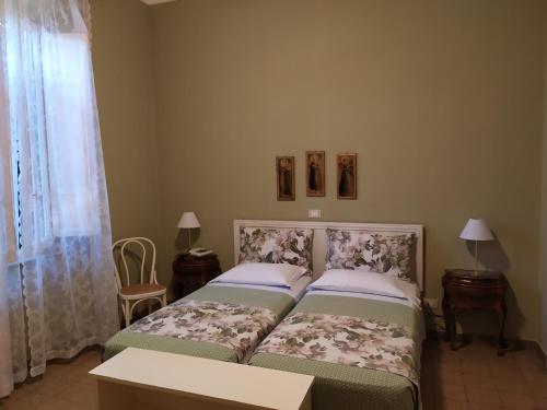 马里纳-迪-皮特拉桑塔Albergo Grande Italia的一间卧室设有两张床、两张桌子和窗户。