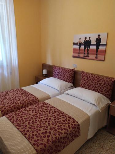 马里纳-迪-皮特拉桑塔Albergo Grande Italia的酒店客房设有两张床,墙上挂有绘画作品