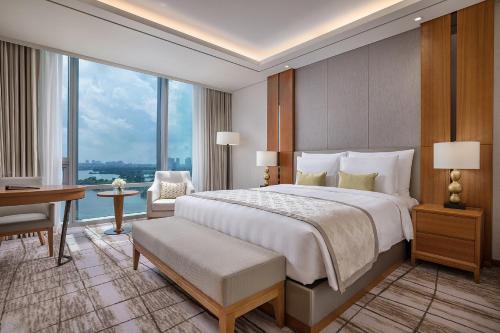 仰光LOTTE Hotel Yangon的一间卧室配有一张大床、一张桌子和一个窗户。