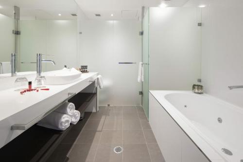 堪培拉东方酒店及公寓的白色的浴室设有2个盥洗盆和1个浴缸。