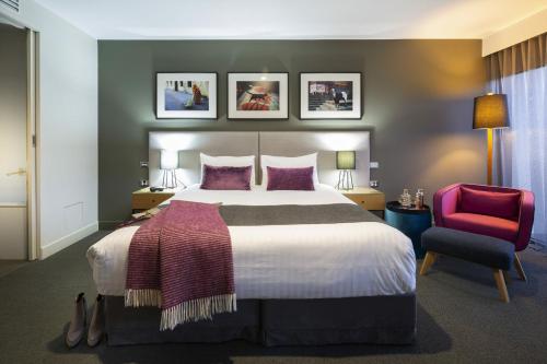 堪培拉东方酒店及公寓的一间卧室配有一张大床和一张红色椅子